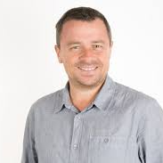 Person smiling, wearing a light gray shirt against a white background.
