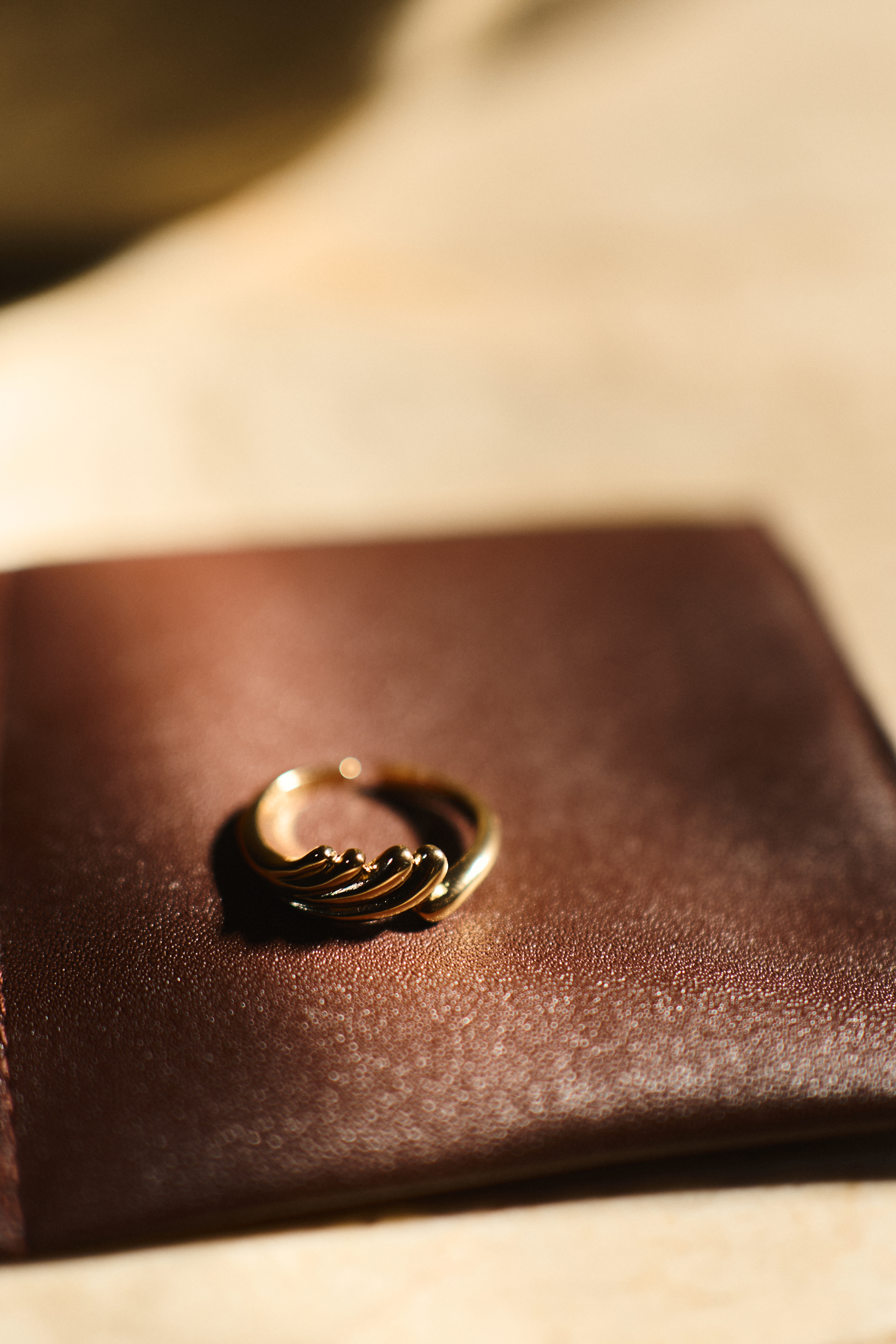 Gold ring on a brown leather surface.