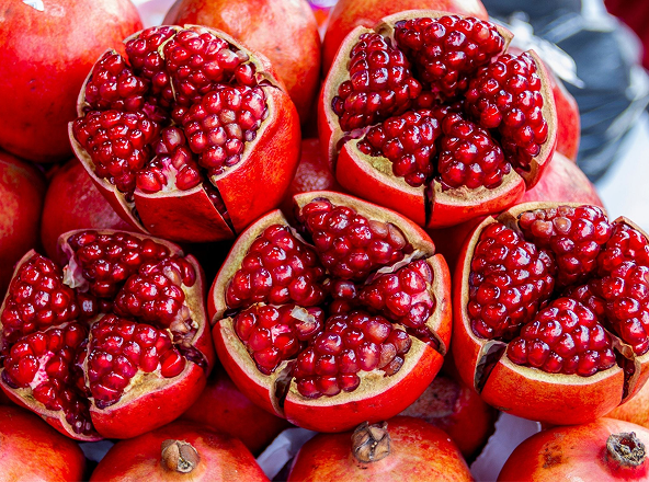 Open pomegranates displaying red seeds surrounded by whole fruit.
