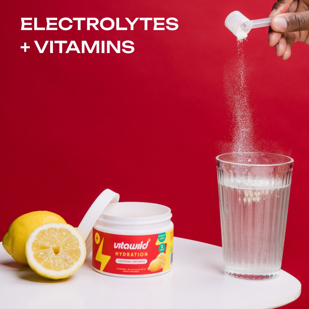 Powder being poured into a glass of water beside a lemon and supplement container.