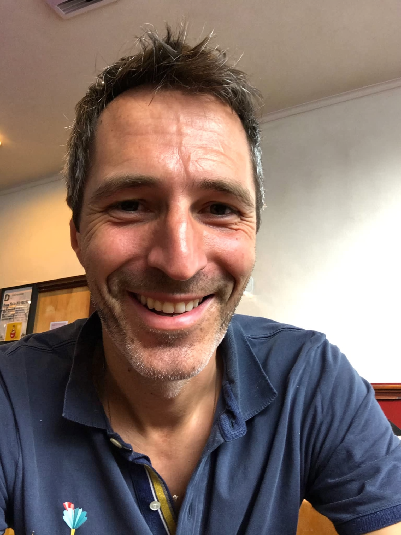 Smiling person in a blue shirt indoors.