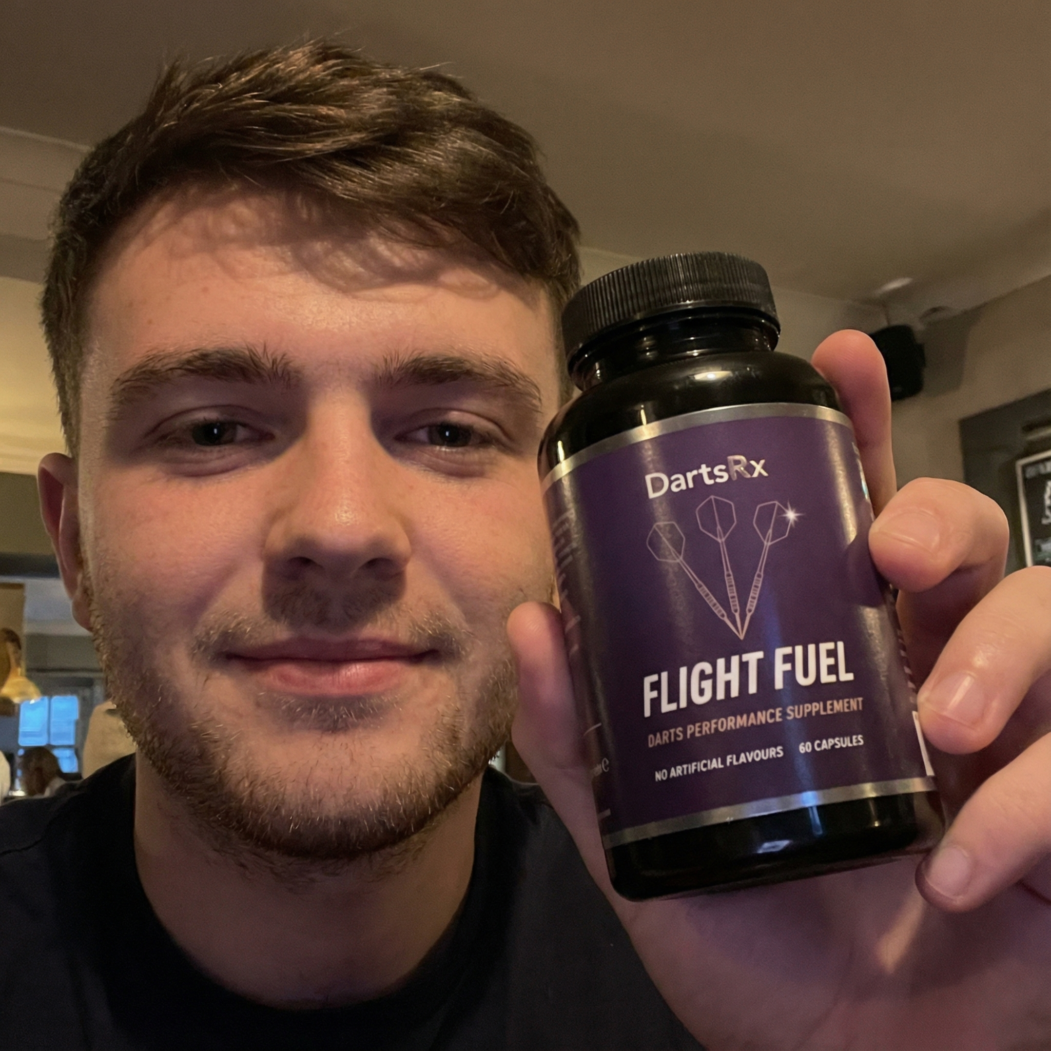 Person holding a bottle labeled 'Flight Fuel' darts performance supplement.