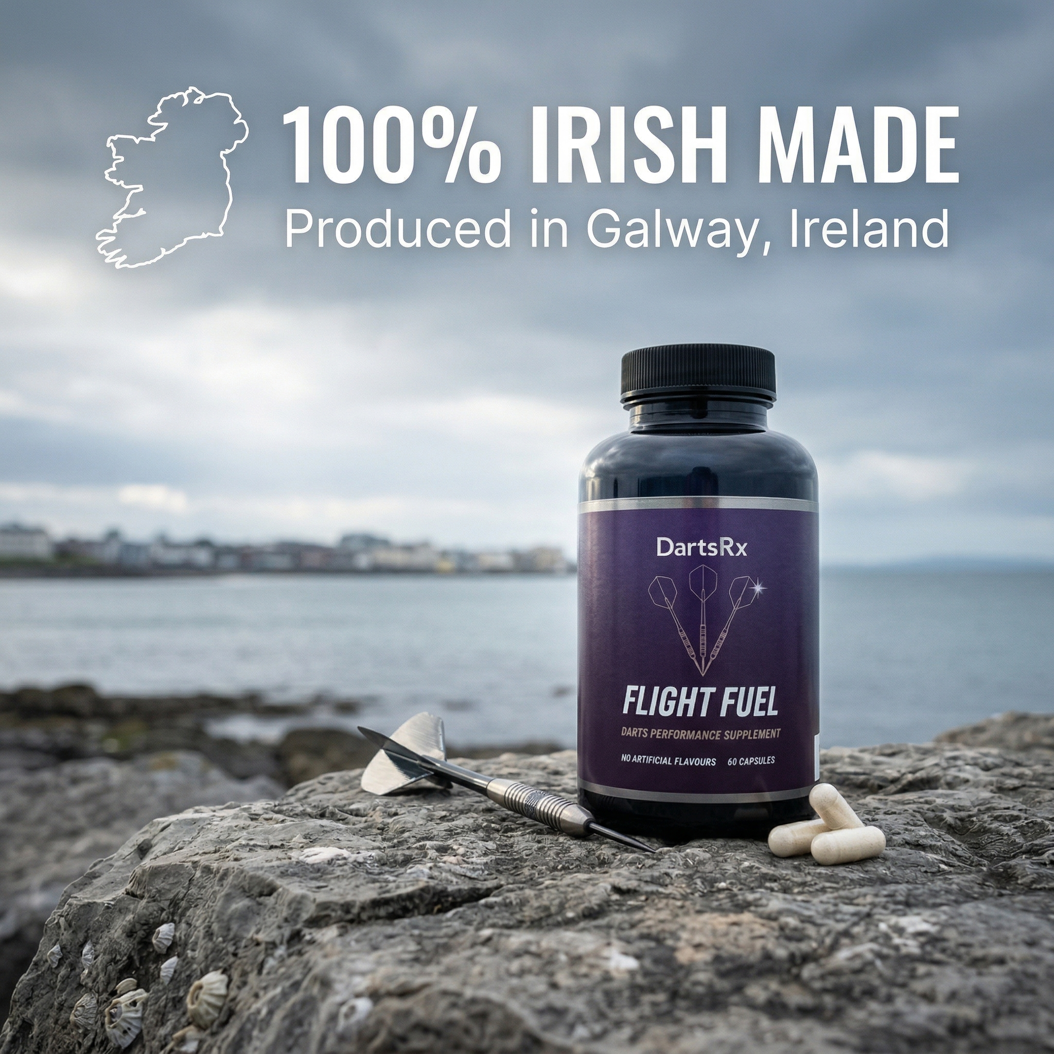 A bottle of DartsRx Flight Fuel supplement, a dart, and two capsules resting on a rock by the sea.