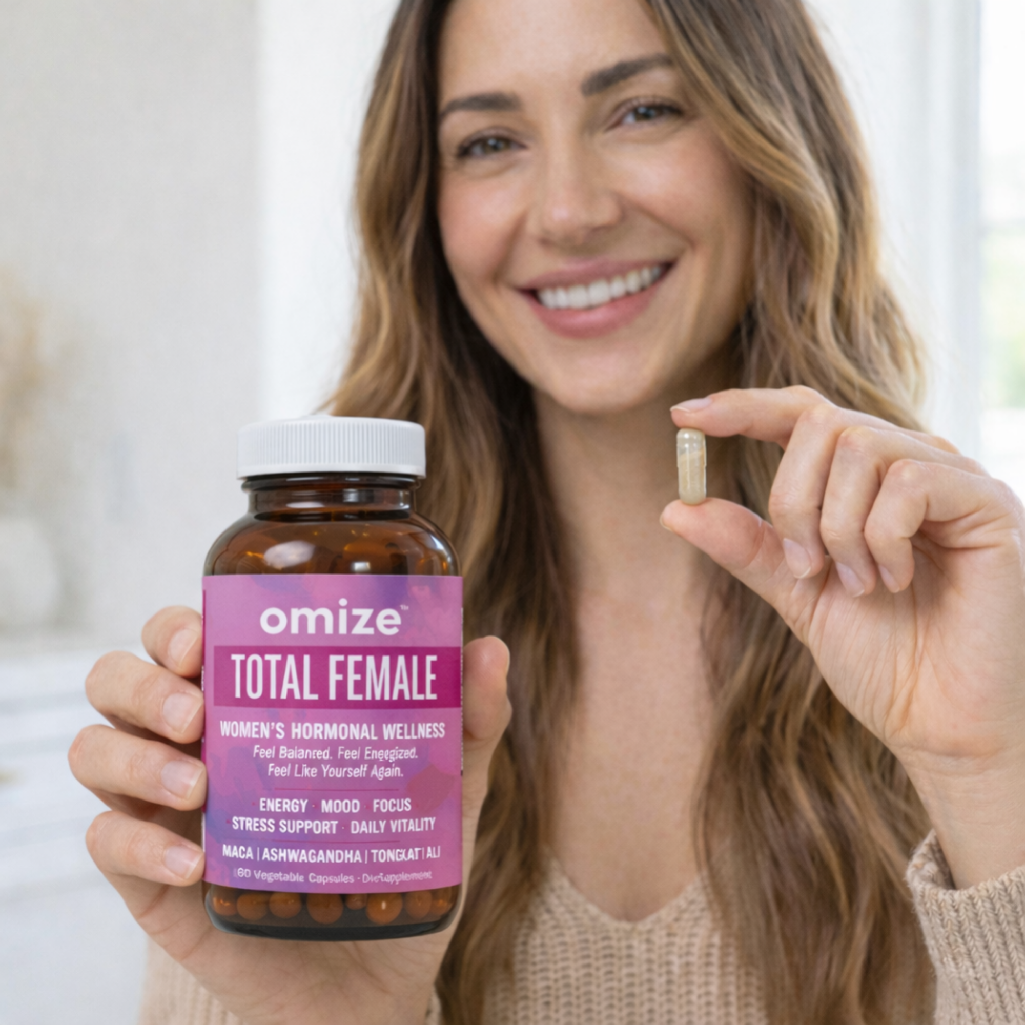 A smiling woman holds a bottle of Omize Total Female supplements and shows a single capsule.