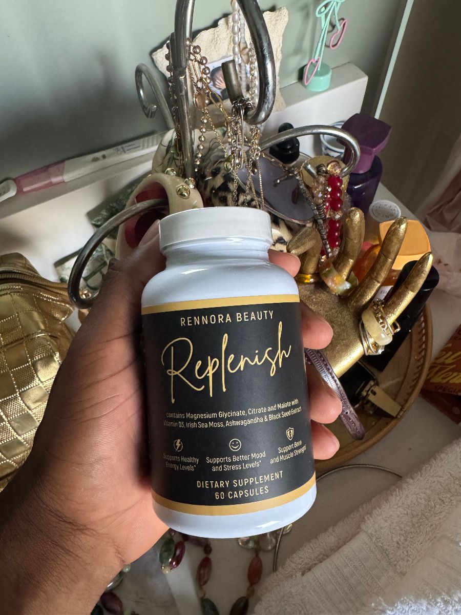 Hand holding a bottle of Rennora Beauty dietary supplement among jewelry and personal items.