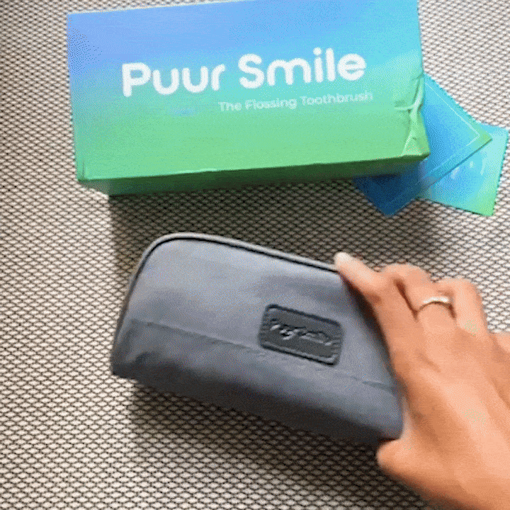 Hand holding a gray pouch next to a Puur Smile toothbrush box.