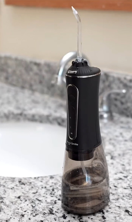Black and transparent water flosser on a granite bathroom countertop.