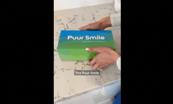 Hands opening a green and blue 'Puur Smile' box on a countertop.