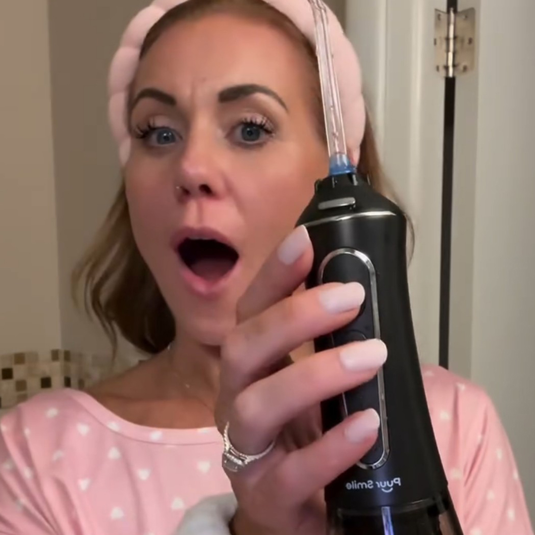 Person in pink headband holding a black dental water flosser.