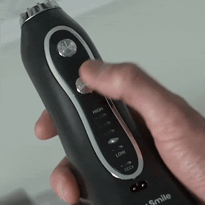 Hand adjusting settings on a black electronic device with buttons.
