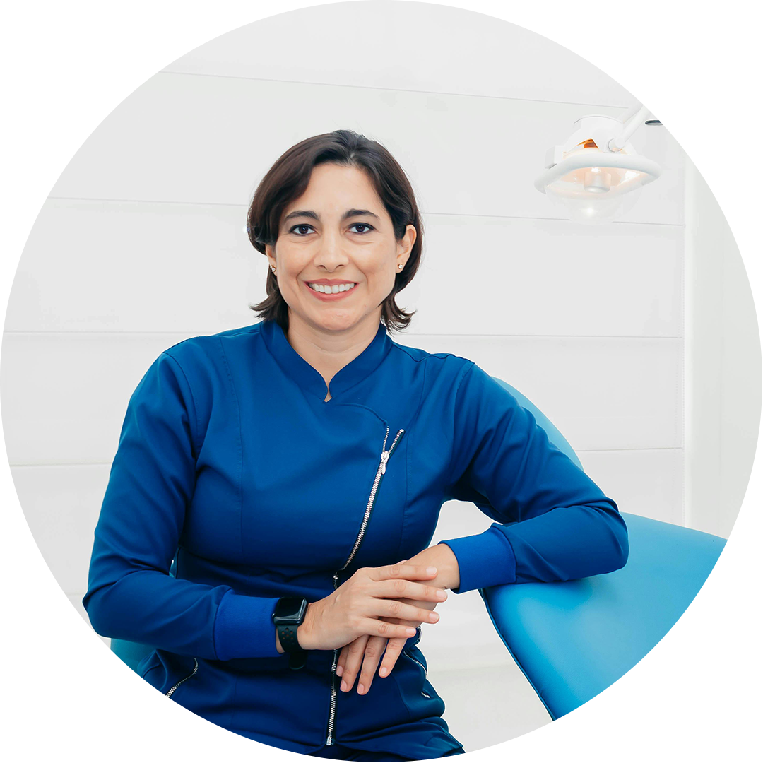 Smiling person in blue attire sitting in a bright, modern environment.