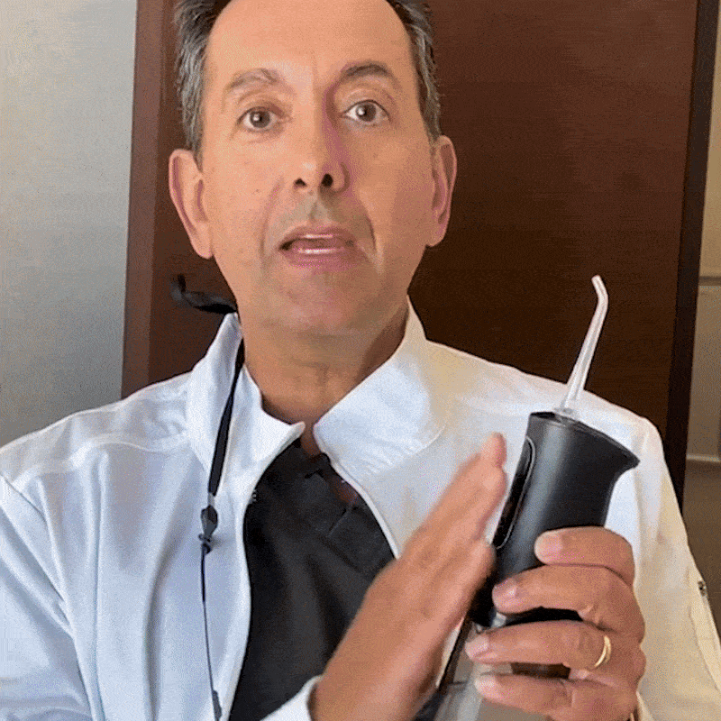 Person in white coat holding a dental water flosser.