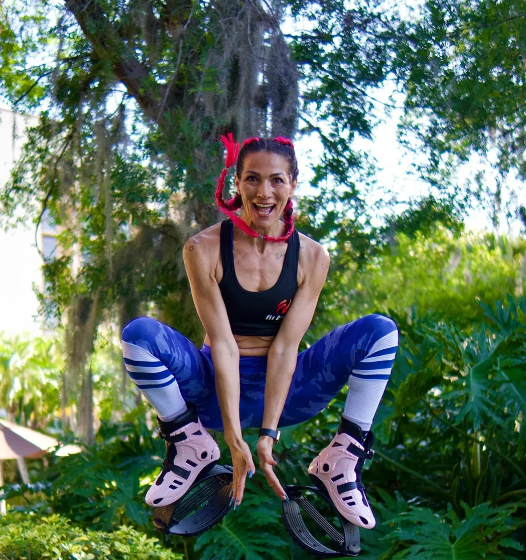 A woman in athletic wear smiles while sitting on a chair and putting on rebound shoes.