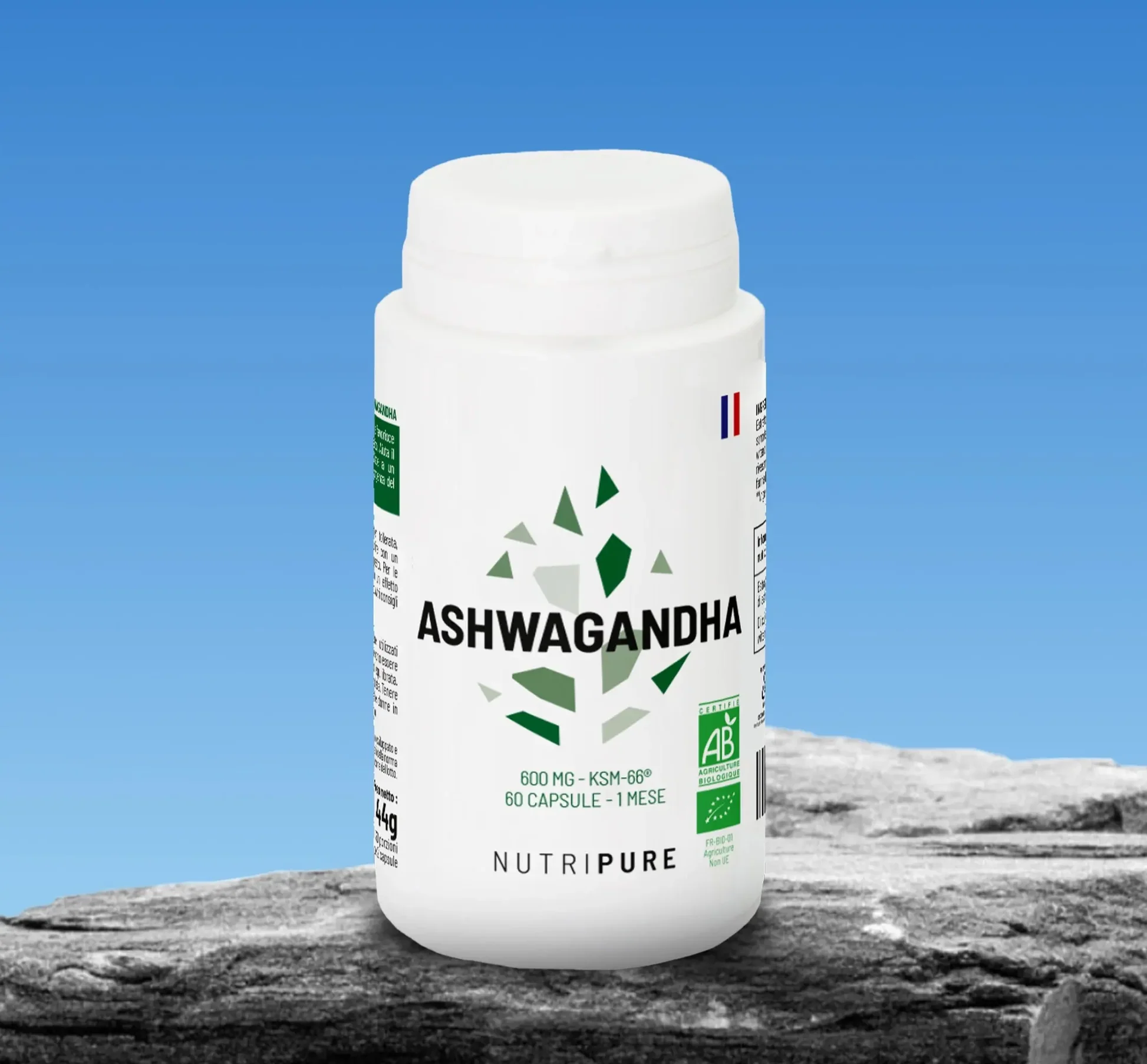 A white bottle of Nutripure Ashwagandha supplements sits on a rock against a blue sky.