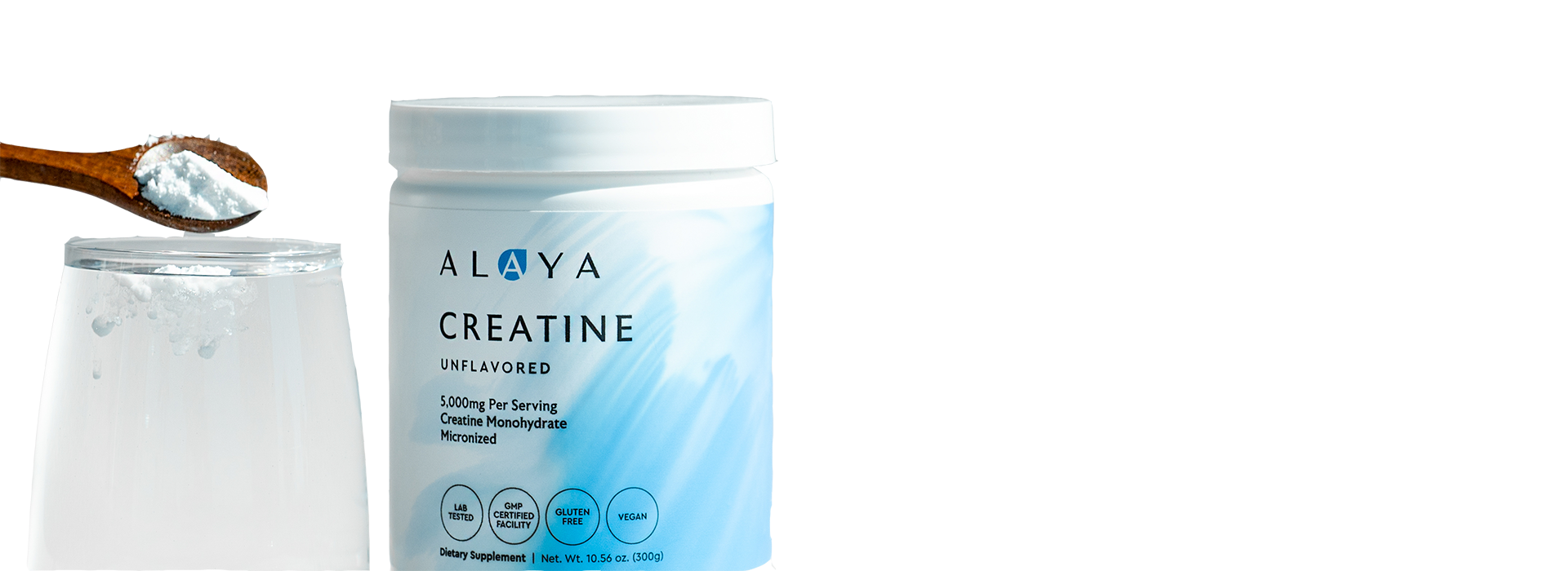 A container of Alaya Creatine next to a glass of water with powder being added from a spoon.