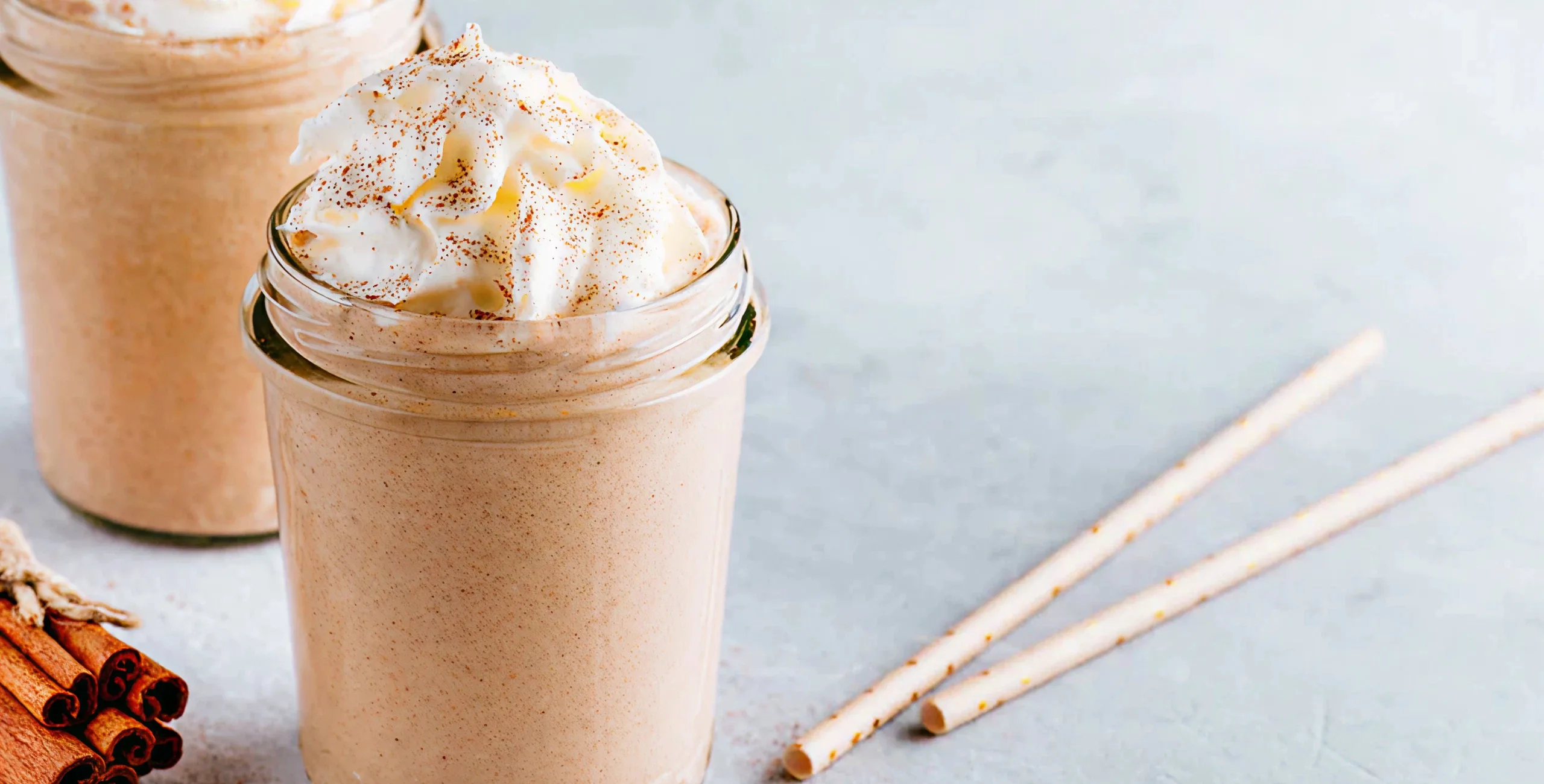 Jar of whipped topping with cinnamon sticks beside it.