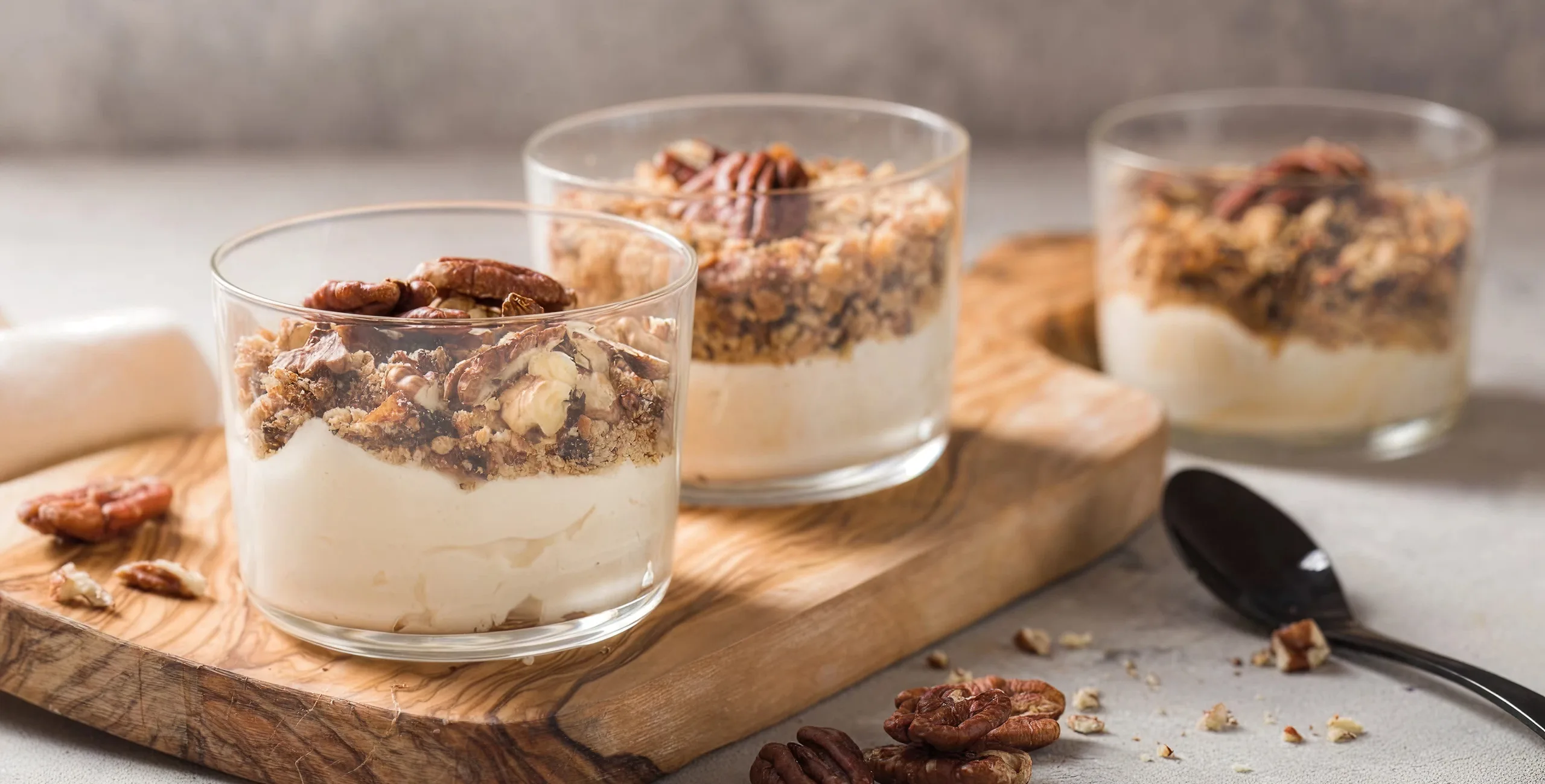 Three dessert glasses with creamy base and pecan topping.