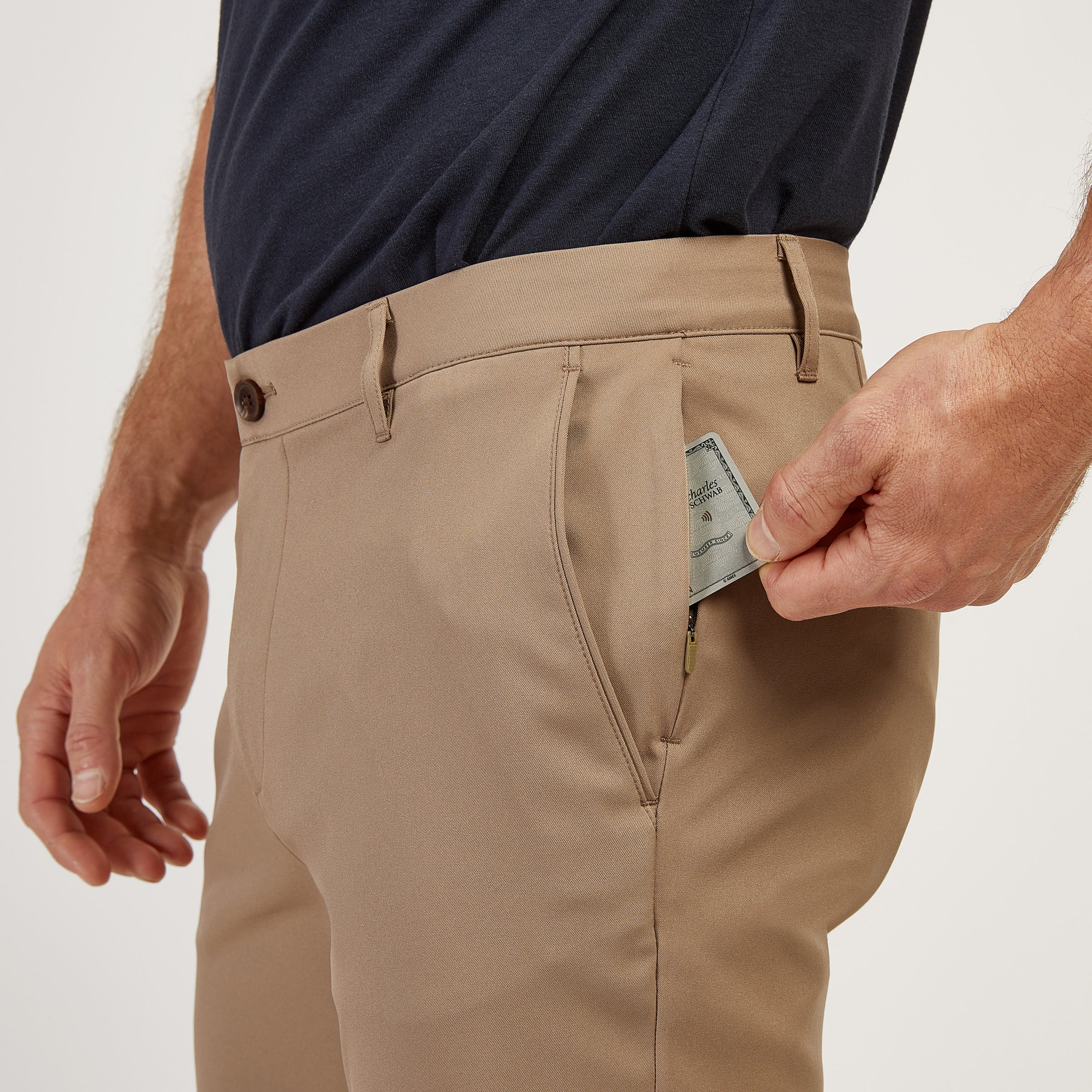 Person placing a bill into the pocket of beige pants.