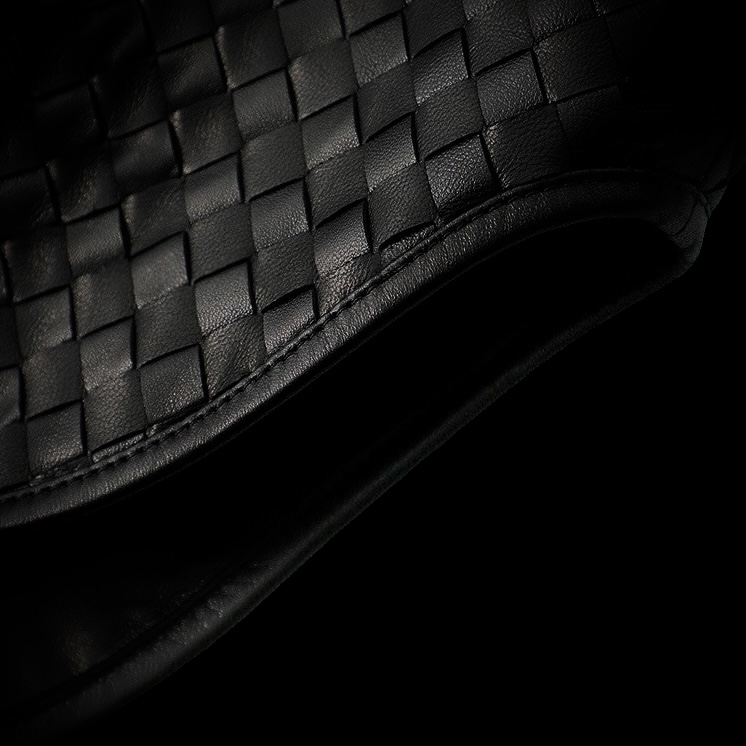 Close-up of black woven leather texture on a curved surface.