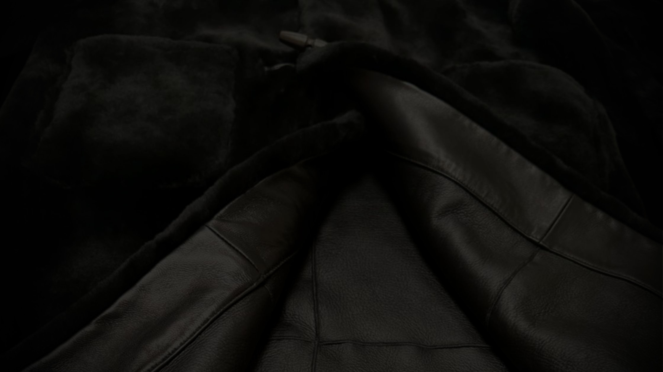 Close-up of black leather and fur fabric with stitching.