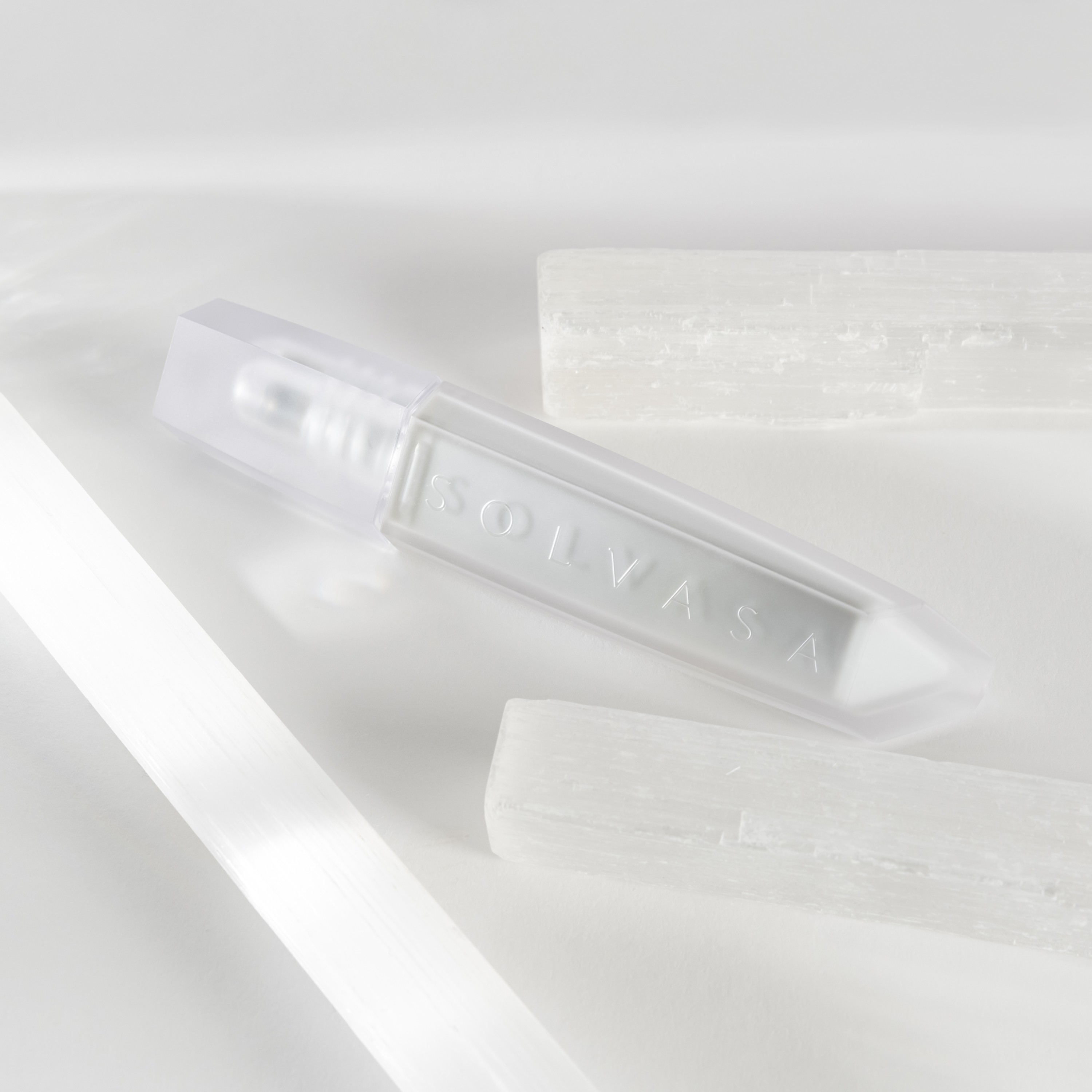A white, crystal-shaped tube labeled SOLVASA lies on a white surface surrounded by raw white crystals.