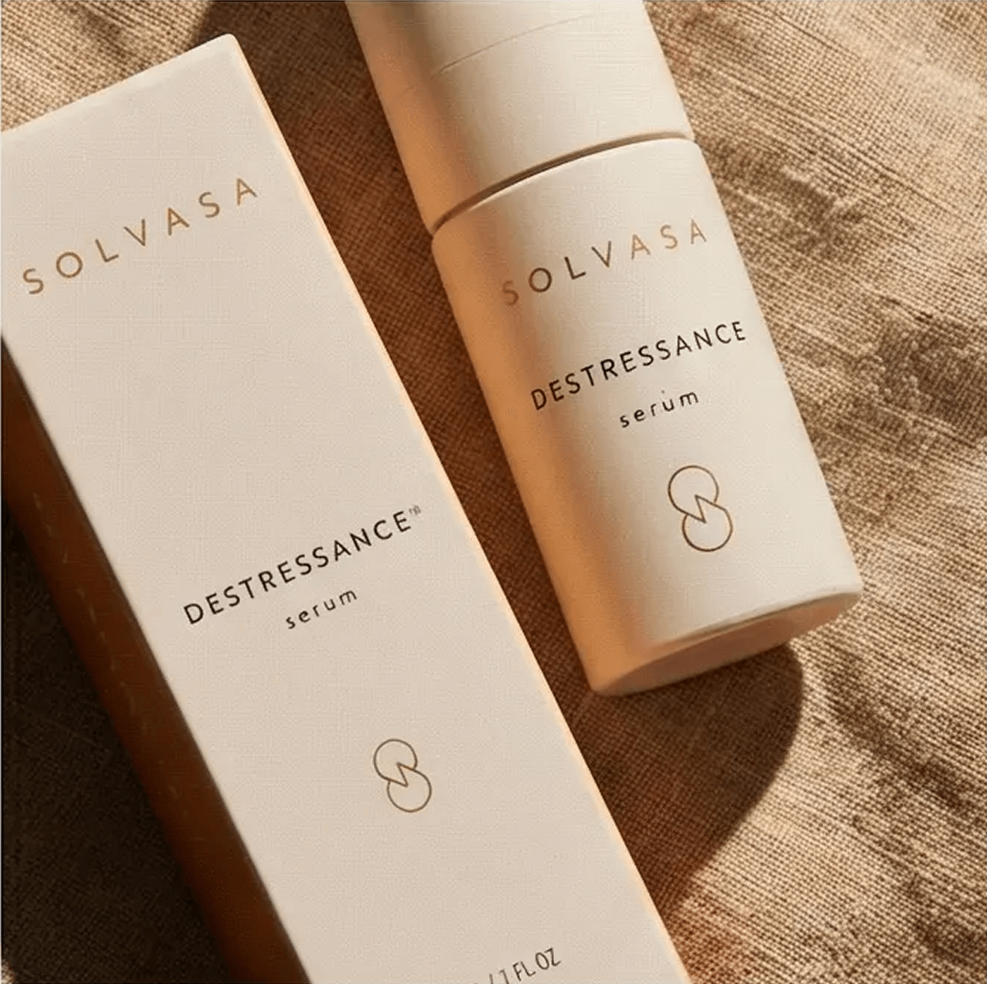 A bottle of Solvasa Destressance serum and its box are displayed on a textured fabric background.