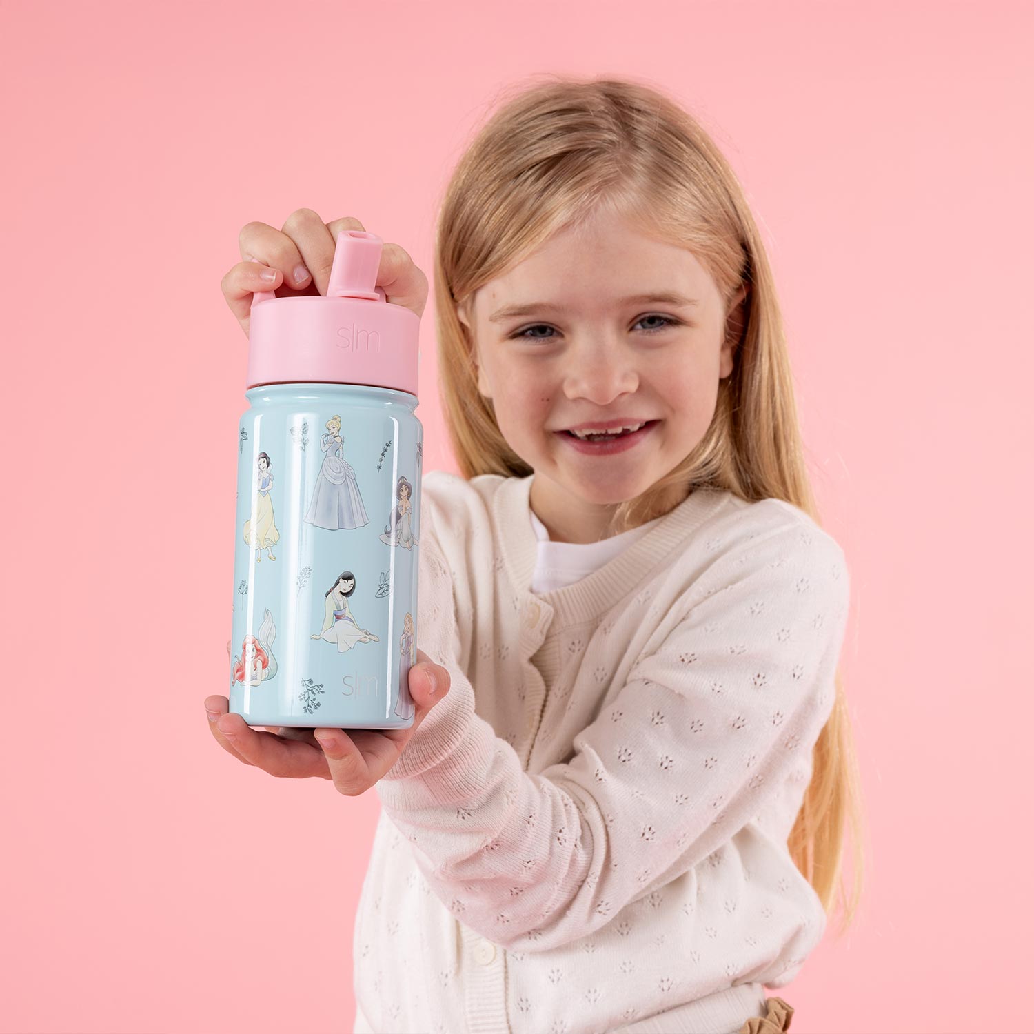 Child holding a decorated water bottle against a pink background.