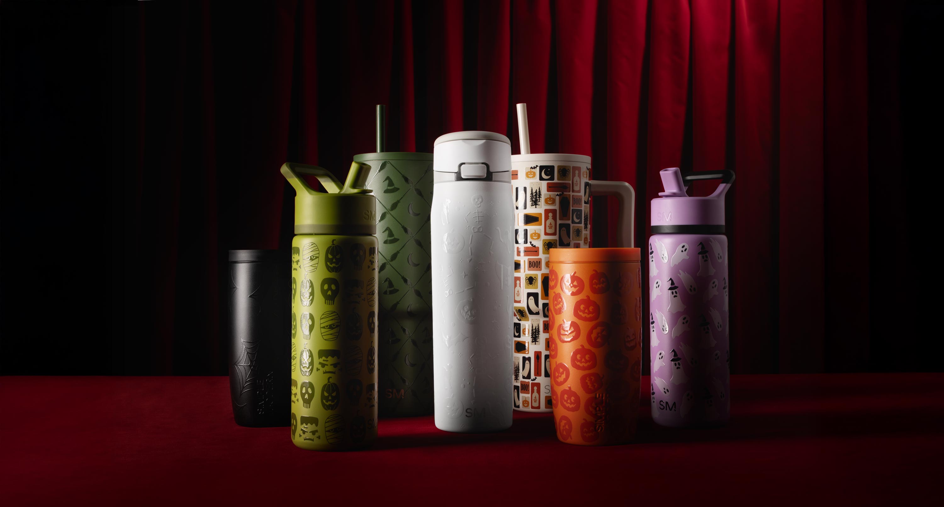 Colorful Halloween-themed bottles against a red curtain backdrop.