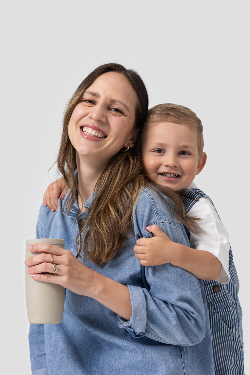 A woman holds a floral water bottle while sitting on a park bench next to a young girl.