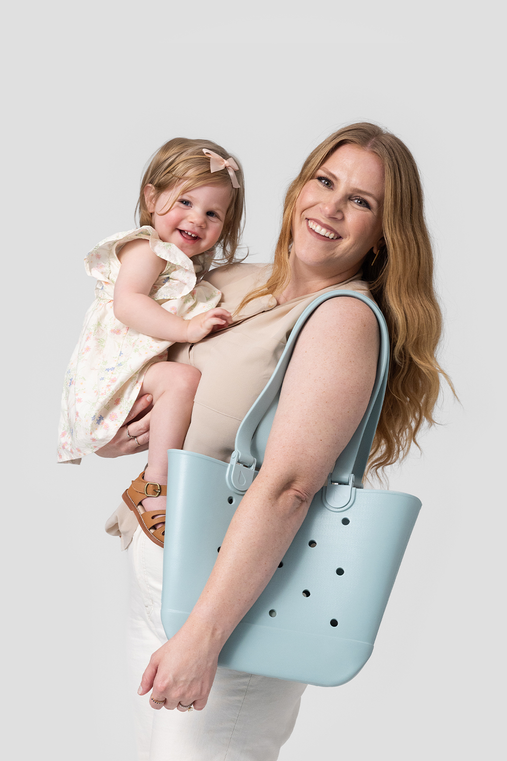 A person holds a baby on their hip while carrying a white floral water bottle.