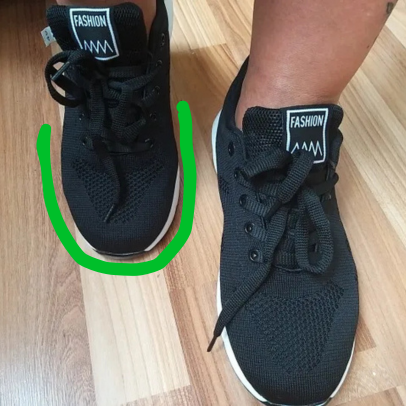 Black sneakers with 'Fashion' label on wooden floor.