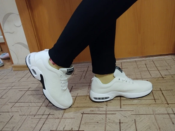 Person wearing white sneakers and black leggings indoors.
