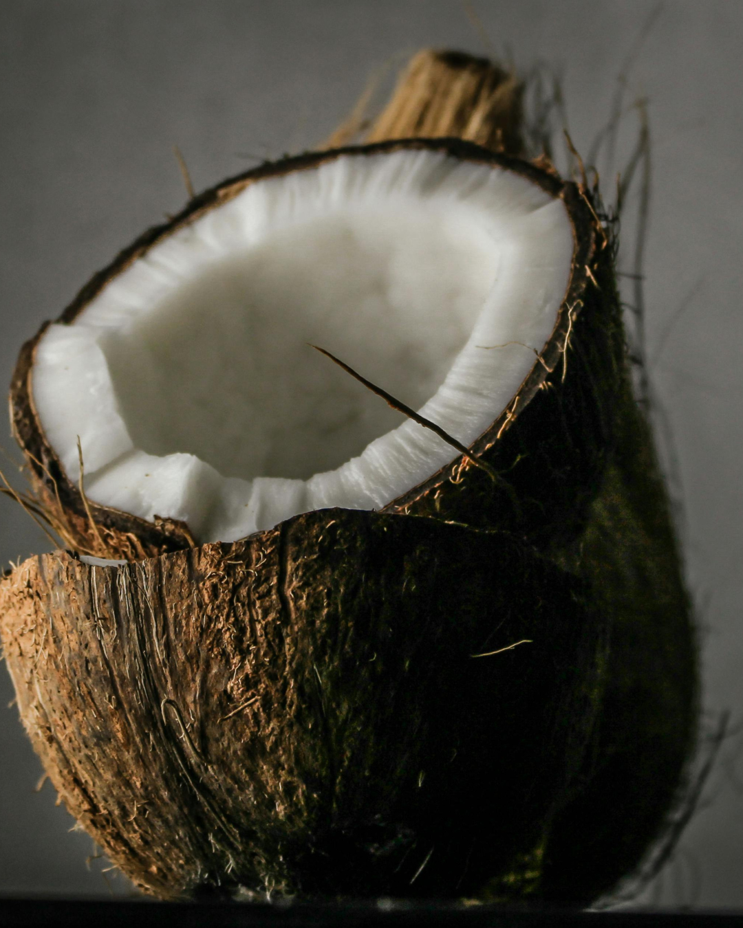 Close-up of a halved coconut with visible white flesh and brown husk.
