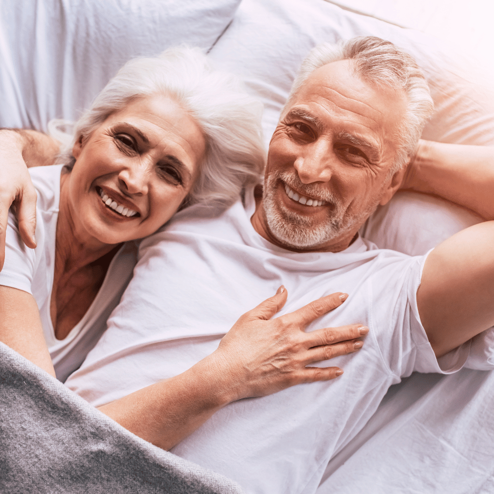 Smiling elderly couple lying together in bed.