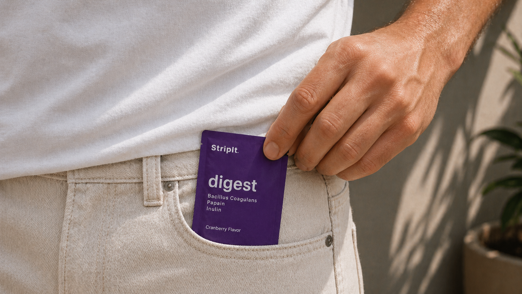 A hand puts a purple Striplt digest packet into the front pocket of a pair of jeans.