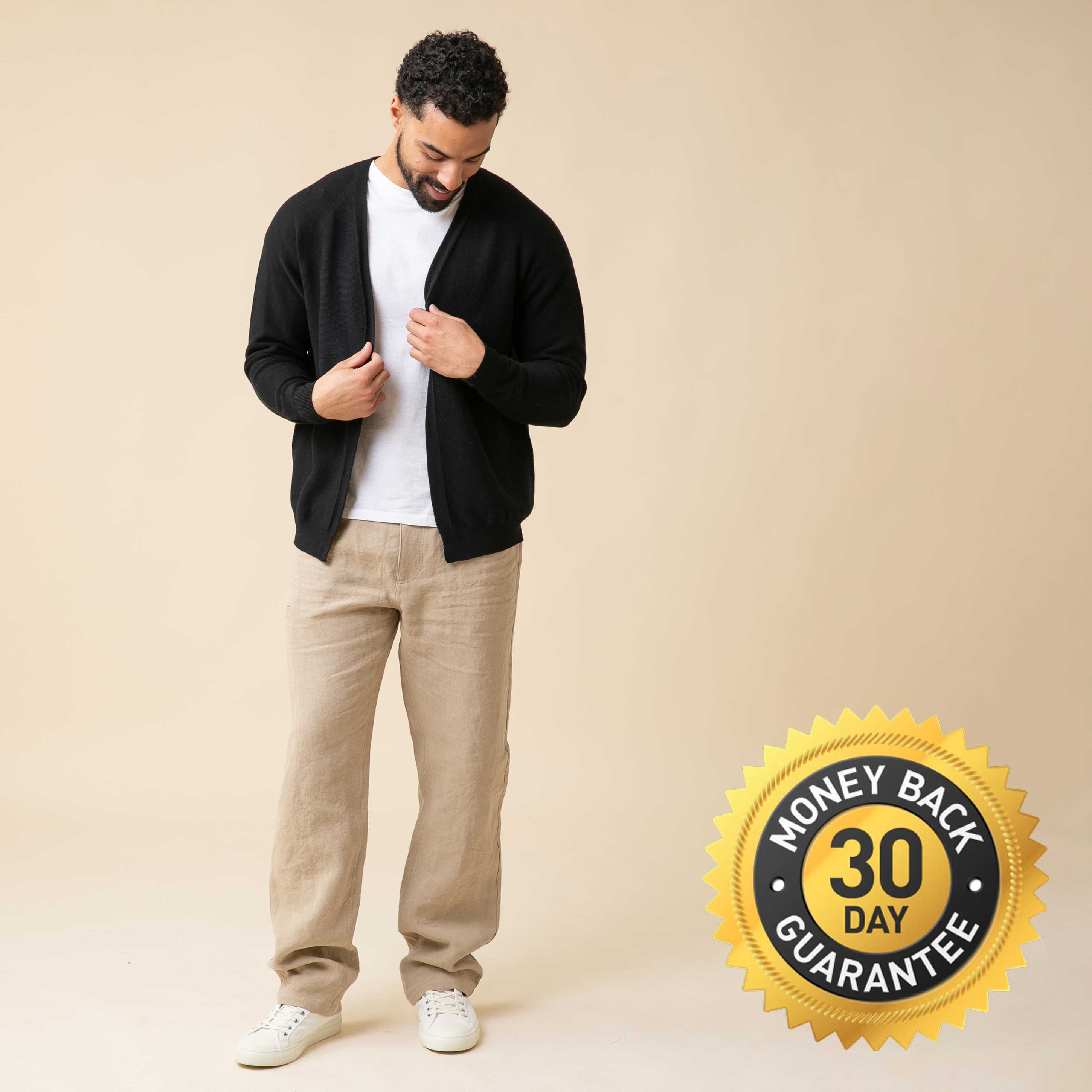A man models a black cardigan, white t-shirt, and tan pants against a beige background.
