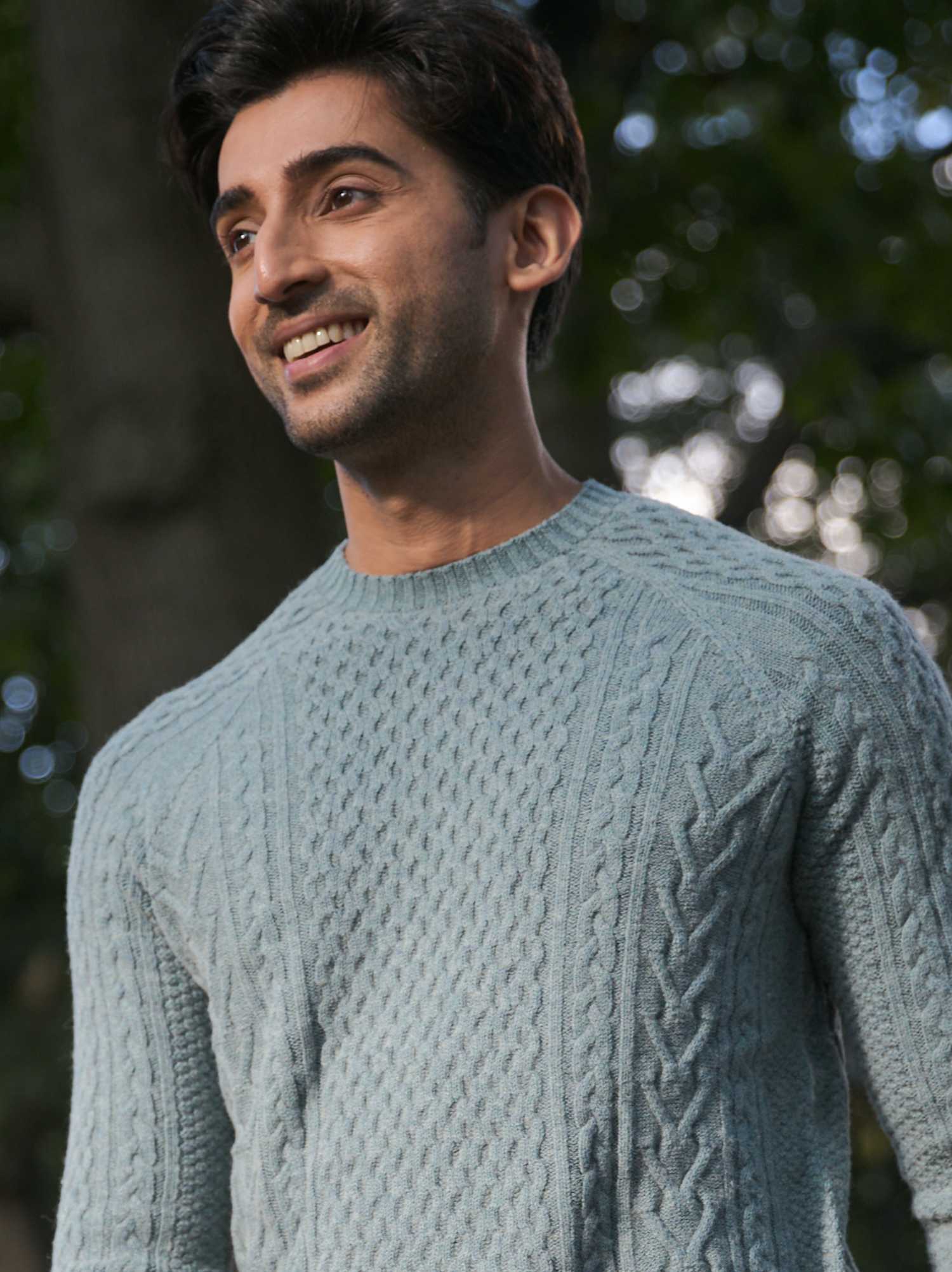 Smiling person in a light blue sweater outdoors.