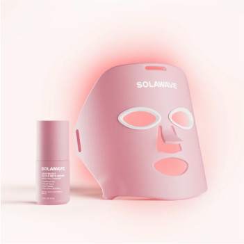 Pink LED face mask and skincare bottle on a light background.