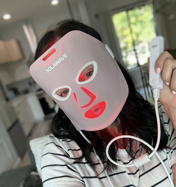 Person wearing a LED light therapy mask in a room.