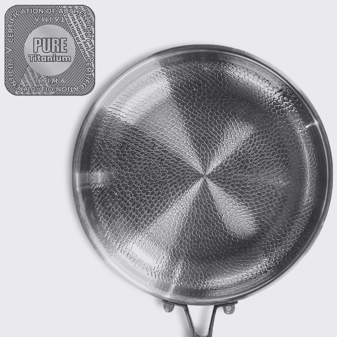 A close-up of a titanium pan with a textured surface and a 'Pure Titanium' certification seal.