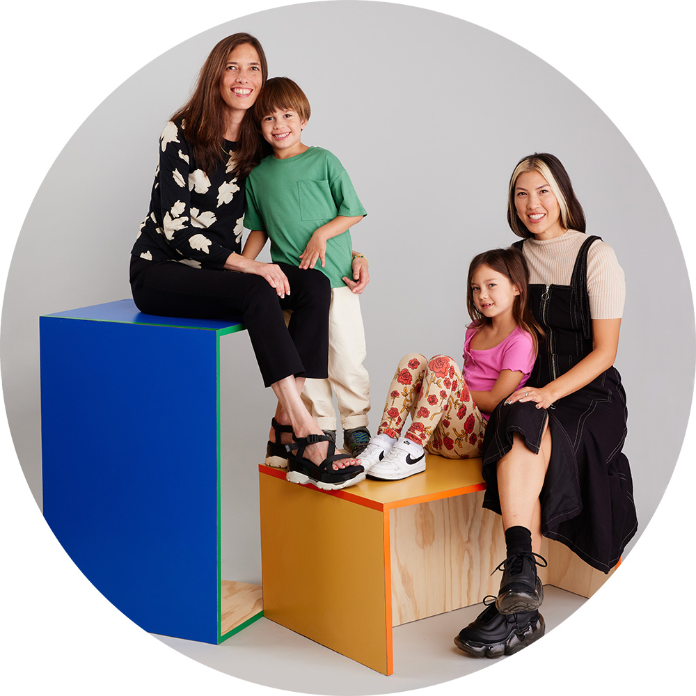 Two adults and two children sitting on colorful cubes in a studio.