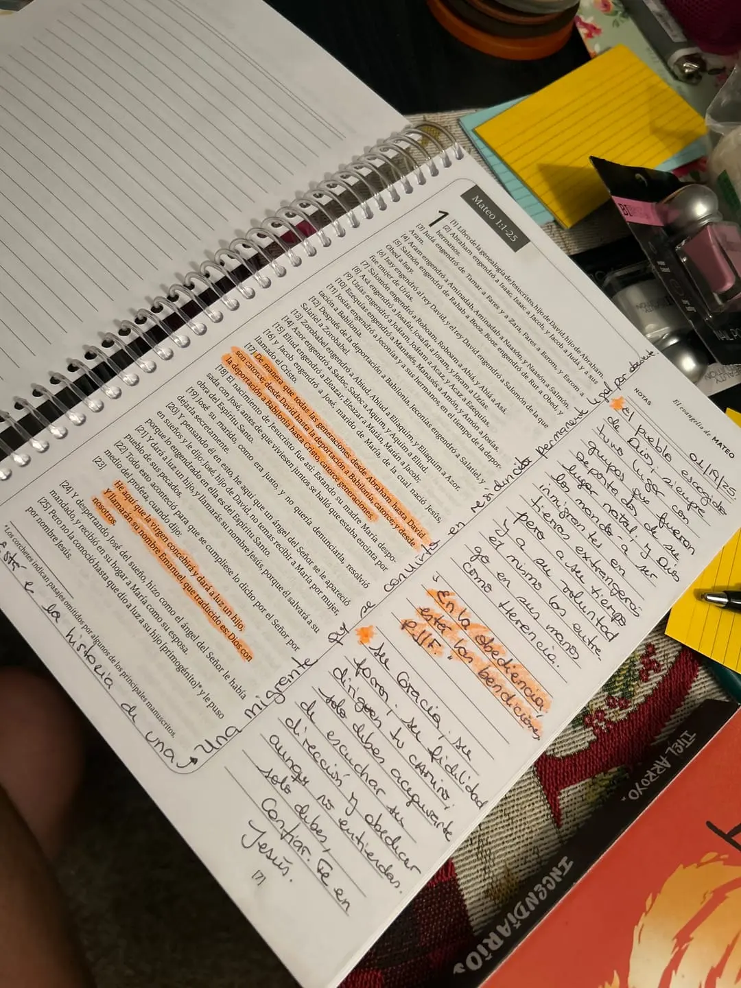 Open notebook with highlighted text and handwritten notes on a cluttered desk.