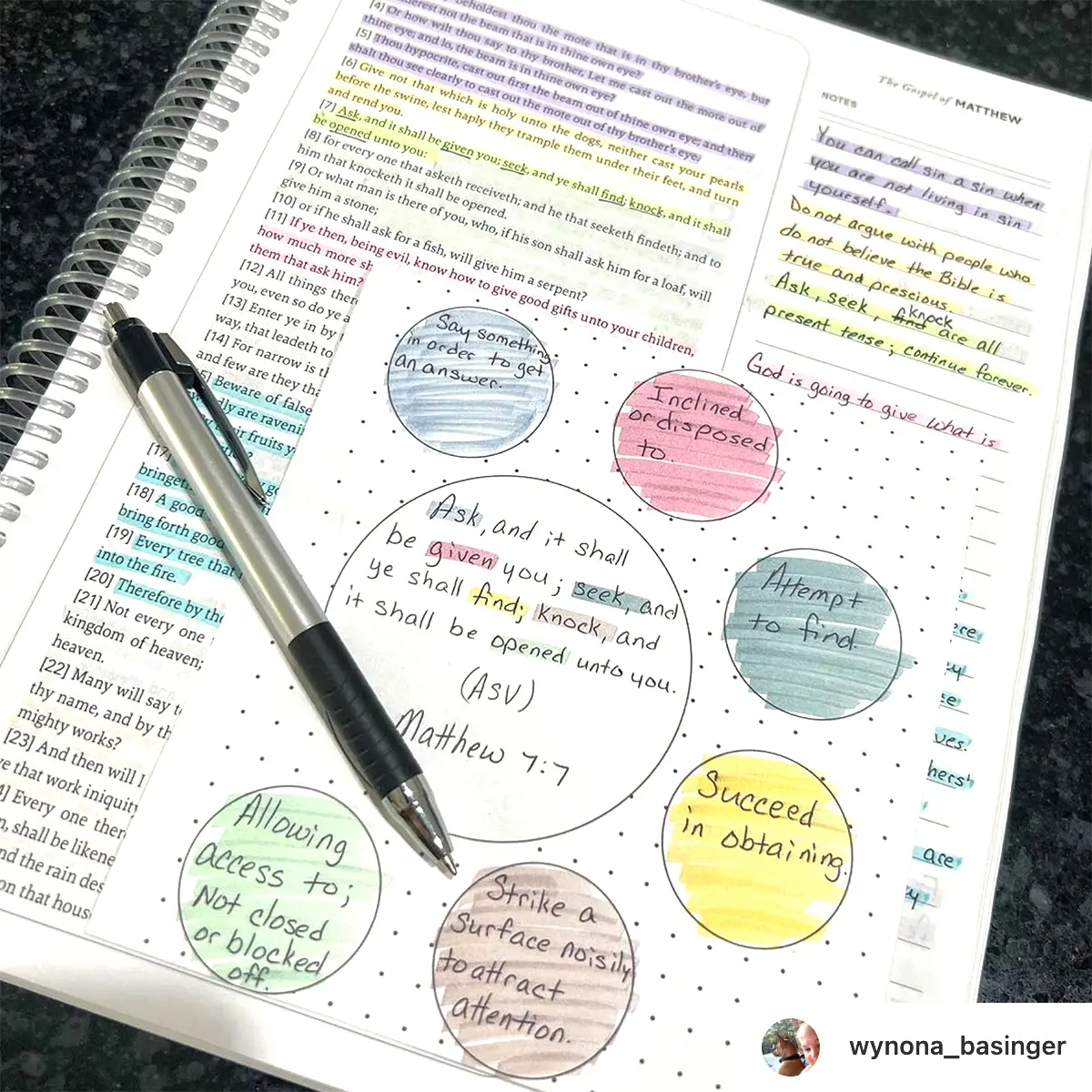 Notebook featuring colorful Bible verse annotations and a pen on a spiral-bound page.