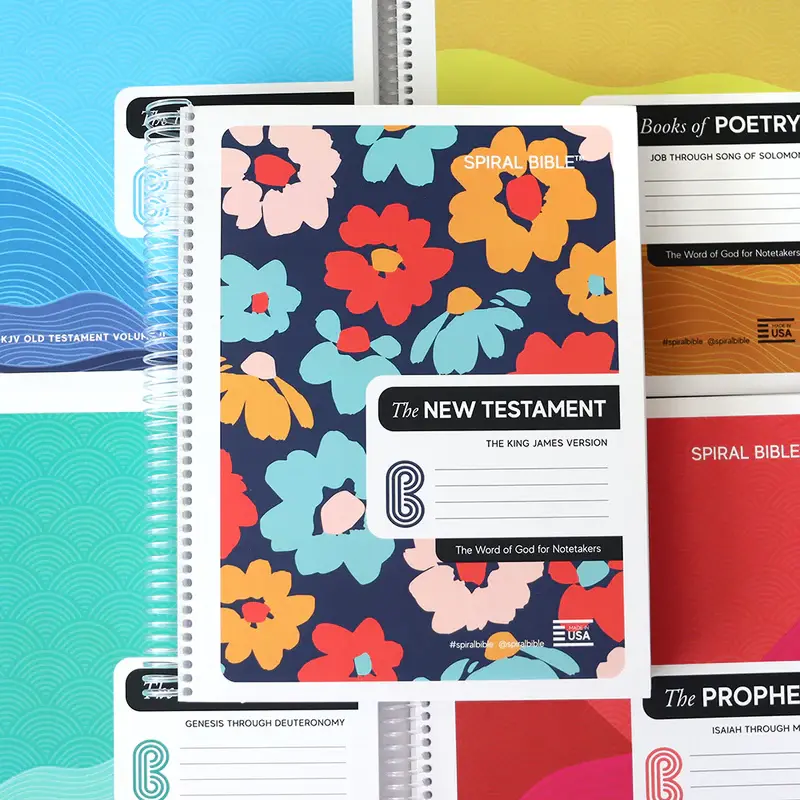 Colorful spiral-bound religious notebooks with floral and wave designs.