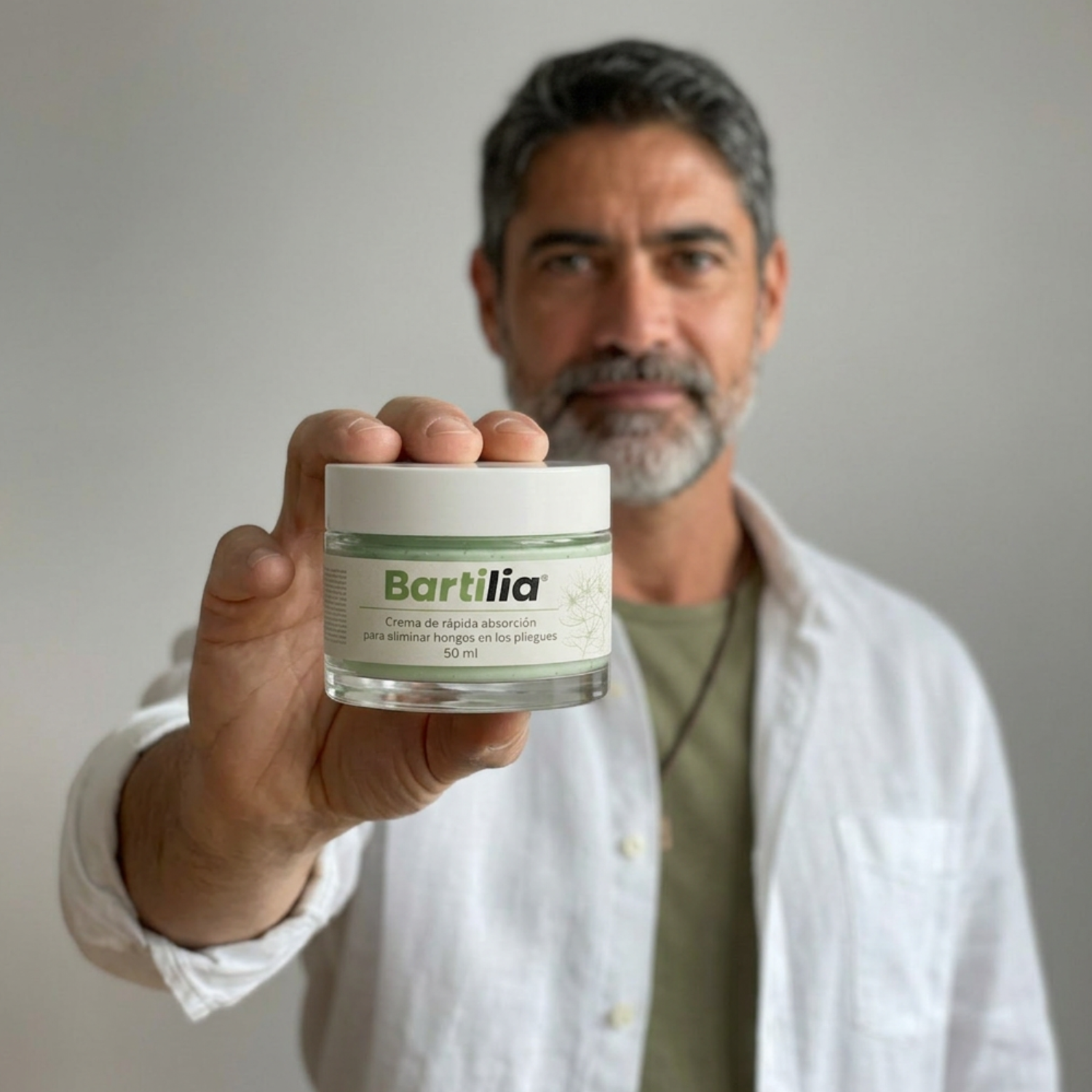 A man with a salt-and-pepper beard holds a jar of Bartilia cream towards the camera.