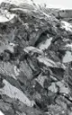 A close-up, black and white photograph of a pile of rough, jagged pieces of material.