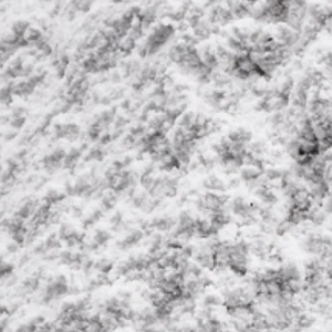 A black and white, close-up photograph showing a lumpy, textured, powdery surface.