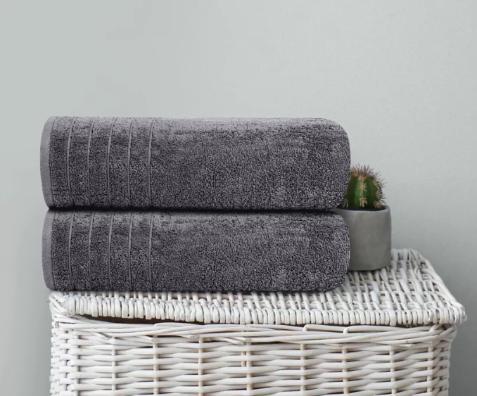 Two folded gray towels on wicker basket beside a small potted cactus.