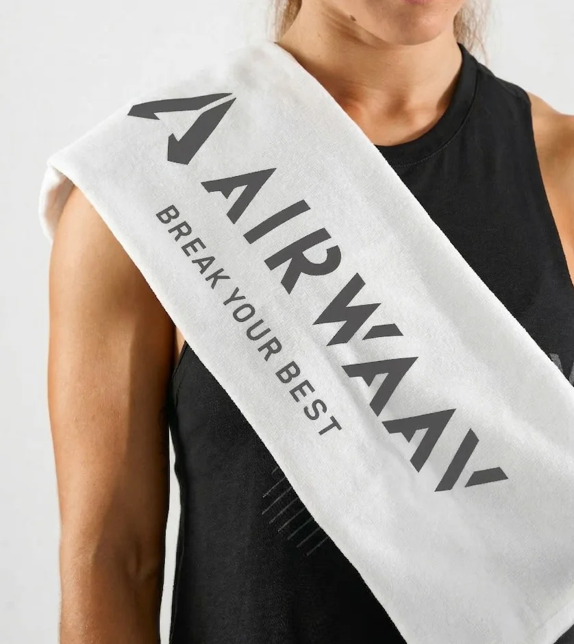 A person wearing a black tank top with a white AIRWAAV brand towel over their shoulder.