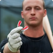 A baseball player wearing a batting glove holds up a small red and white mouthguard.